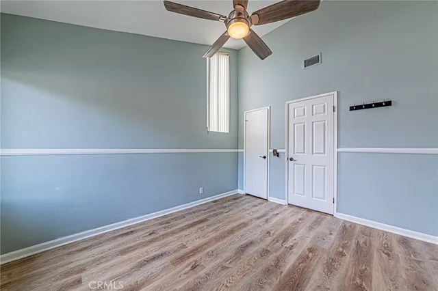 an empty room with wooden floor fan and windows