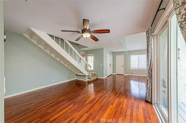 a view of empty room with wooden floor and fan