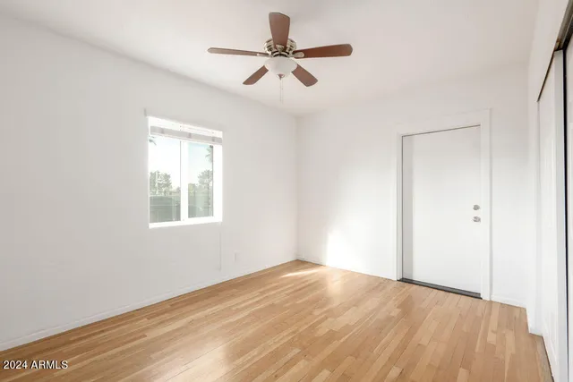 a view of empty room with wooden floor and fan