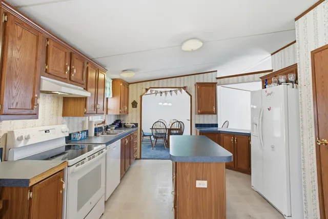 a kitchen with stainless steel appliances a sink a stove a refrigerator cabinets and a window