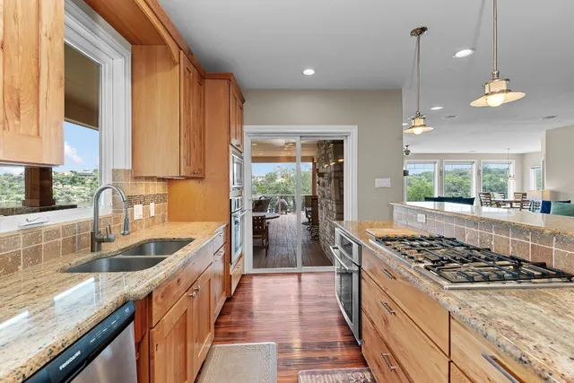 a kitchen with stainless steel appliances granite countertop a sink stove and cabinets
