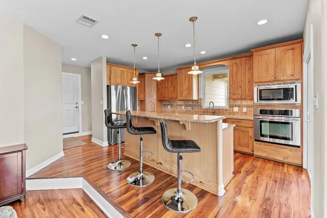 a kitchen with stainless steel appliances kitchen island granite countertop a stove a sink a refrigerator and a microwave