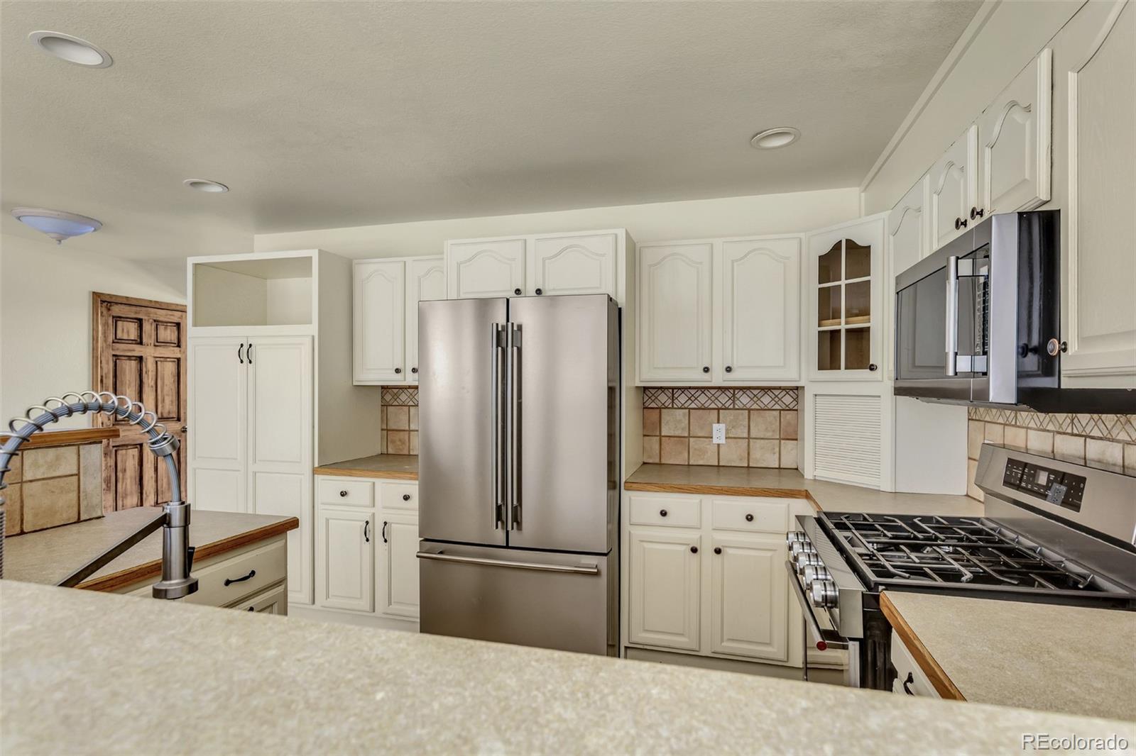 12183 Arnett Ranch Road Littleton, CO 80127 - Photo 11 of 28 a kitchen with stainless steel appliances granite countertop a refrigerator stove and sink
