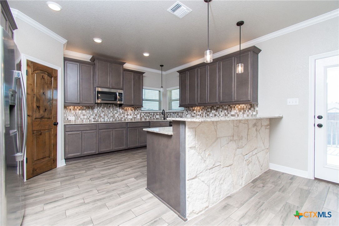 8101 Tenley Way Killeen, TX 76542 - Photo 11 of 29 a kitchen with kitchen island granite countertop wooden cabinets and stainless steel appliances