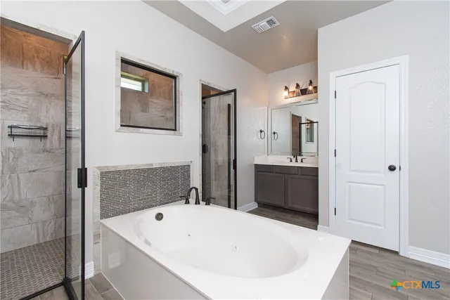 a bathroom with a tub a sink and a mirror