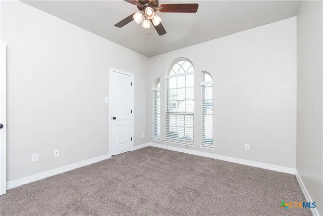 an empty room with windows and chandelier fan