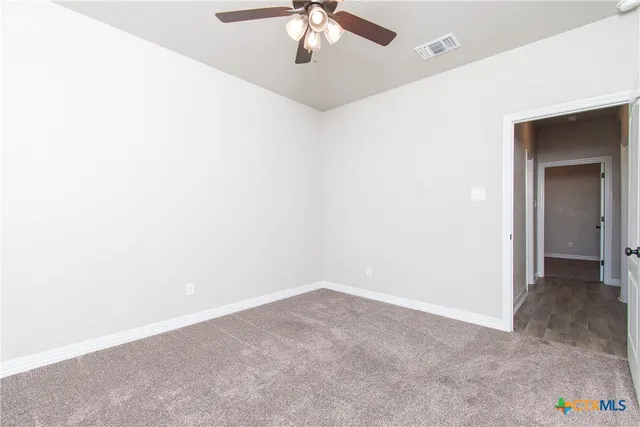 an empty room with a ceiling fan and carpet