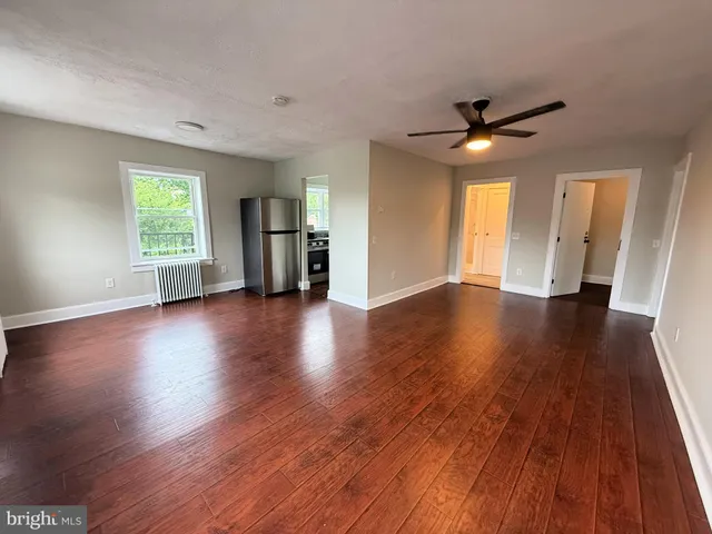 a view of an empty room with window and wooden floor