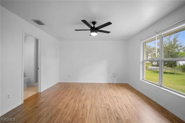 an empty room with a window and a ceiling fan