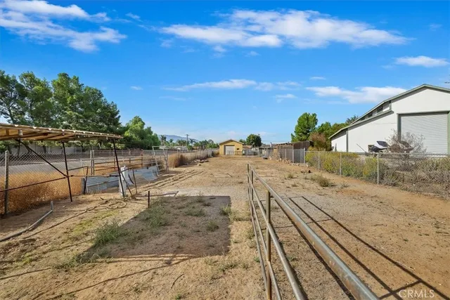 a view of a dry yard with wooden fence