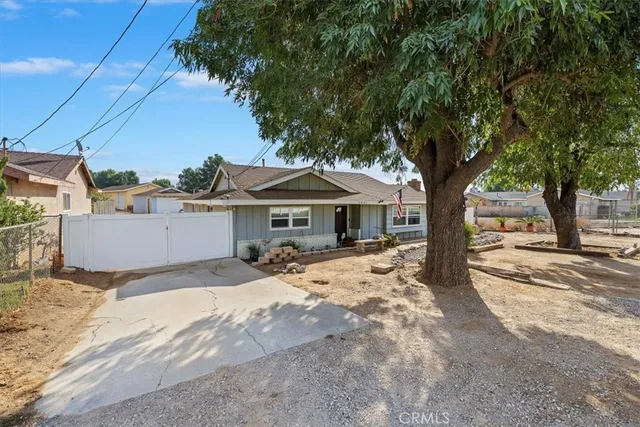 a view of a house with large tree and wooden fence