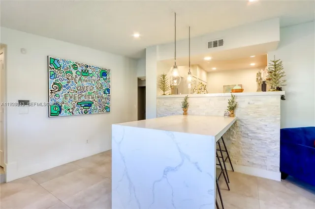 a view of kitchen with kitchen island a island a stove a counter space and a sink