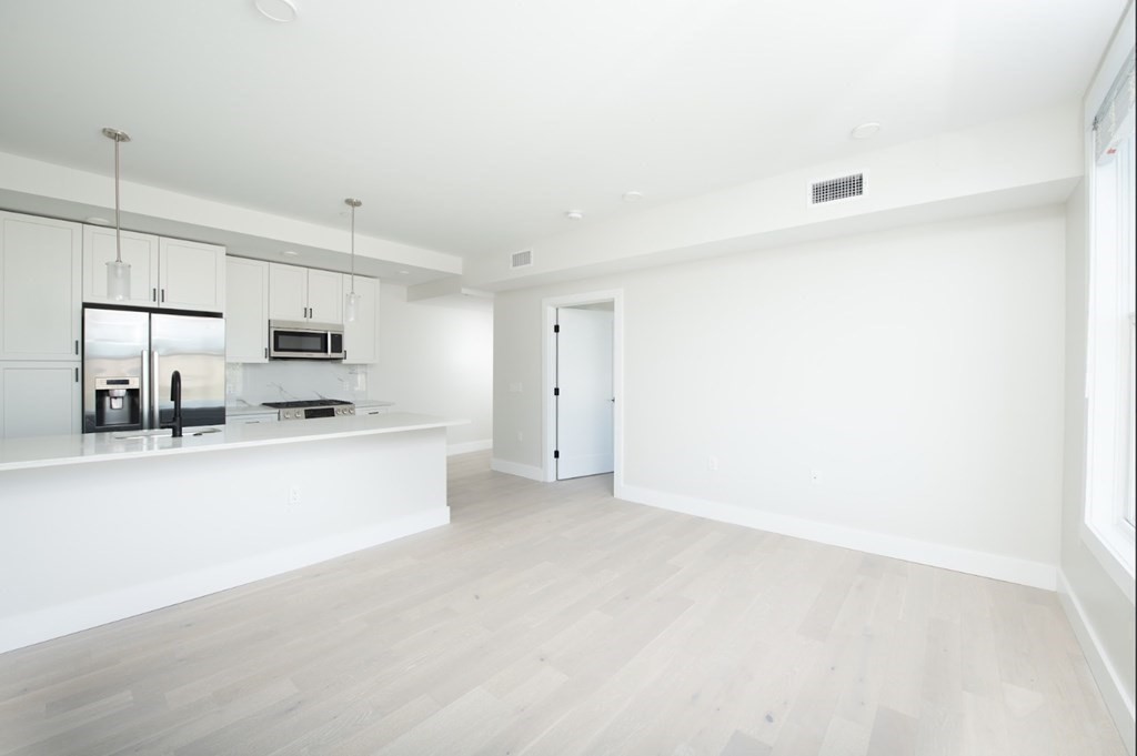 a view of kitchen with stainless steel appliances refrigerator stove microwave and cabinets