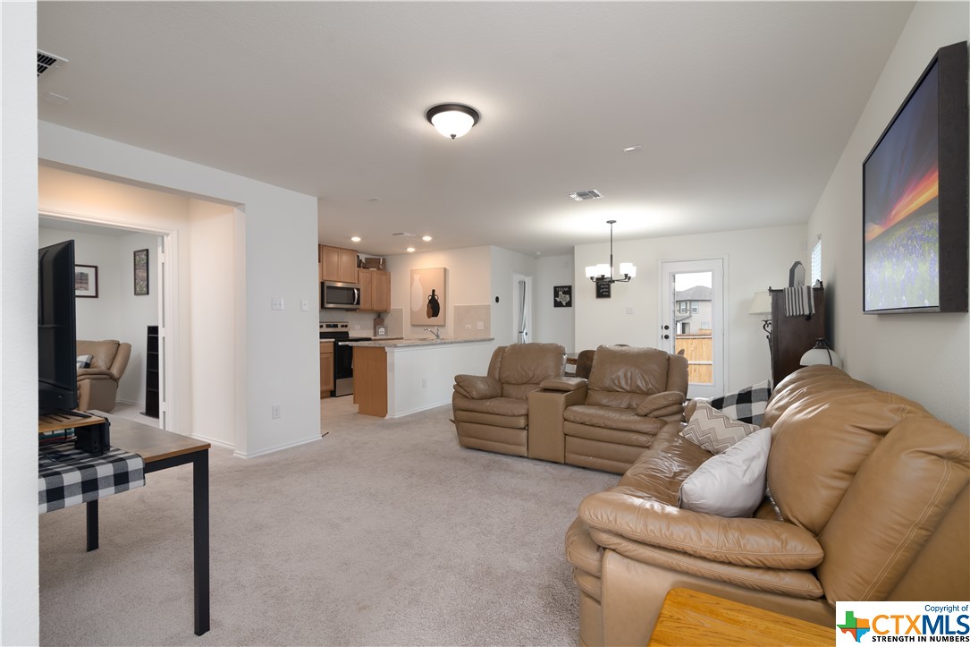 a living room with furniture and a view of kitchen