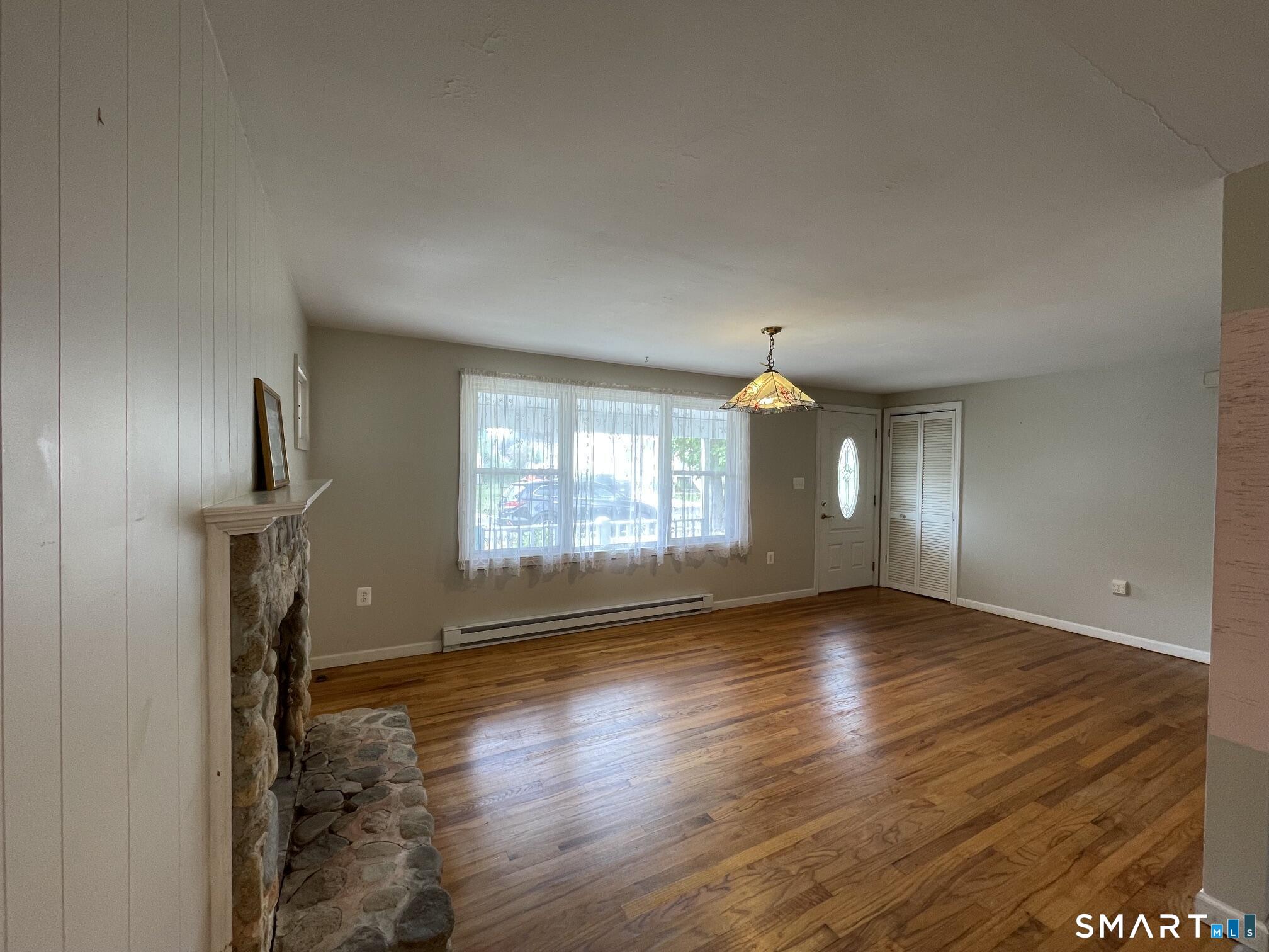 18 Old South Cove Road Old Saybrook, CT 06475 - Photo 10 of 40 an empty room with wooden floor fireplace and windows