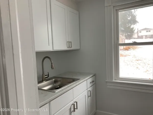 a kitchen with white cabinets and a window