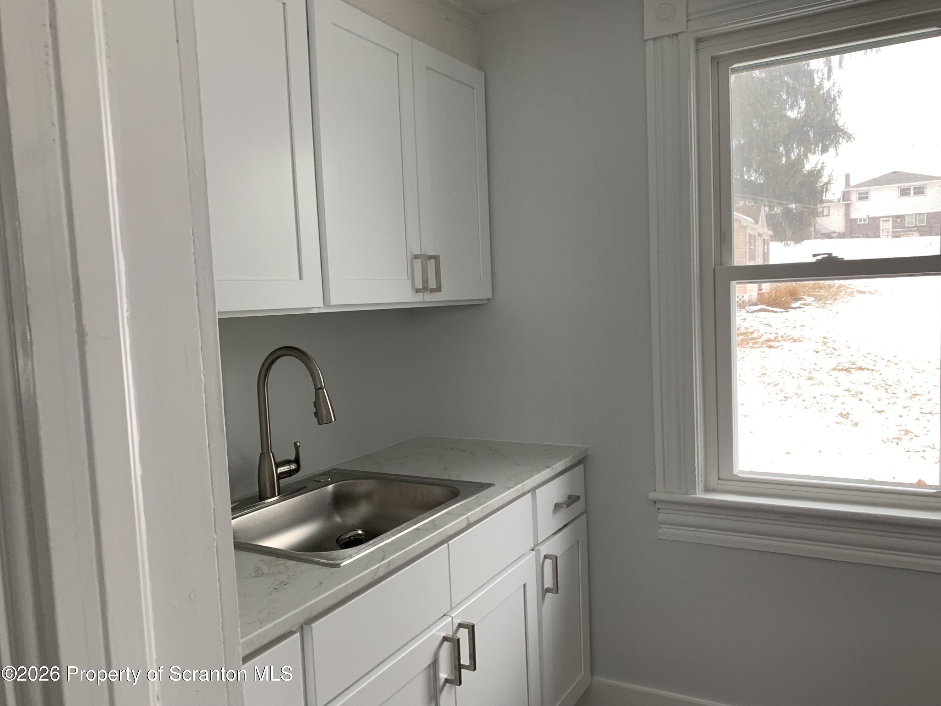 709 Meade Street Dunmore, PA 18512 - Photo 8 of 38 a kitchen with white cabinets and a window