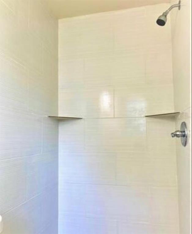 2536 Rutherford Street Irving, TX 75062 - Photo 16 of 19 Shower enclosure featuring white horizontally-laid ceramic tiles and integrated corner shelves