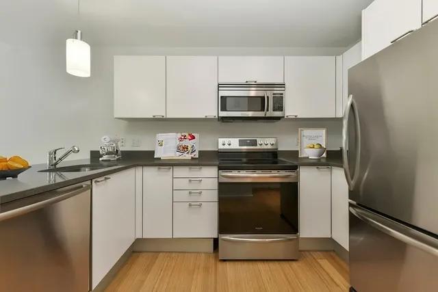 a kitchen with stainless steel appliances granite countertop a refrigerator sink and white cabinets