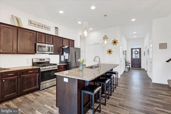 a kitchen with stainless steel appliances a dining table chairs stove refrigerator and cabinets