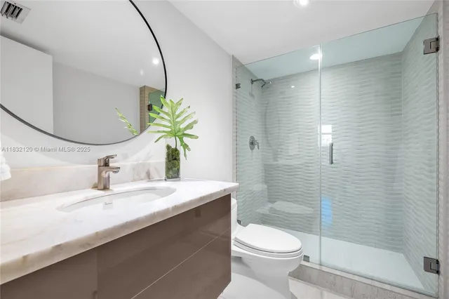 a bathroom with a granite countertop sink a toilet and shower
