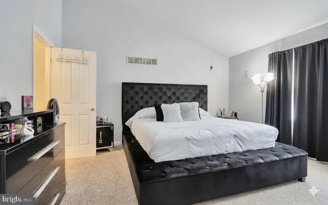 a large bed sitting in a bedroom next to a window with dresser and mirror