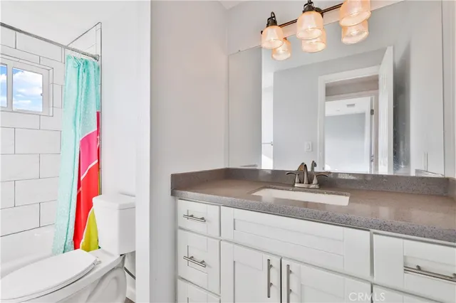 a bathroom with a granite countertop sink a toilet and a mirror