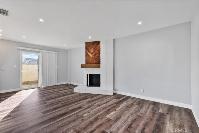 a view of empty room with wooden floor and fireplace