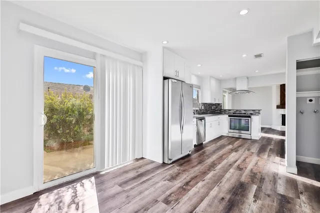 a view of a kitchen with refrigerator and wooden floor