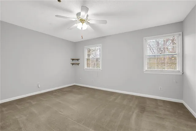 an empty room with windows and fan