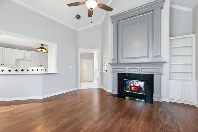 a view of an empty room with wooden floor and a fireplace