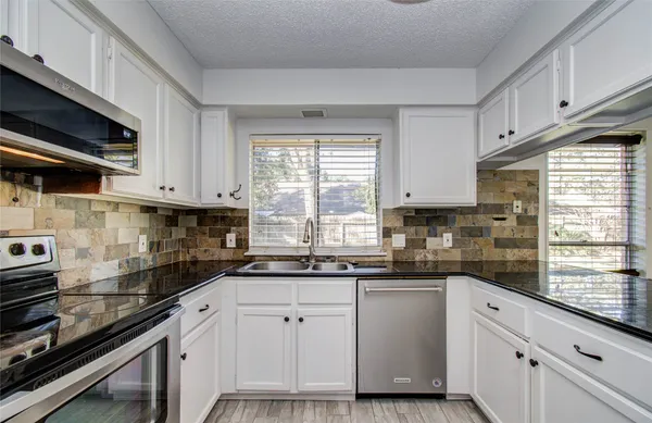 a kitchen with white cabinets and appliances