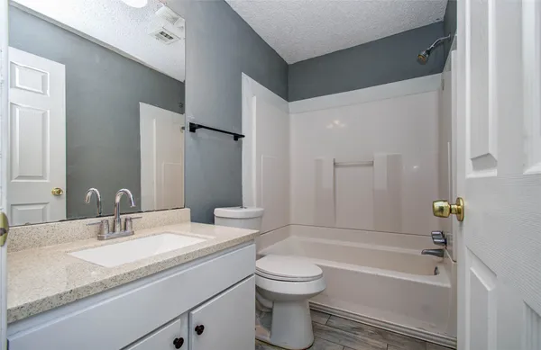 a bathroom with a granite countertop sink toilet and shower