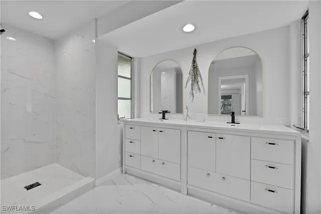 a bathroom with double vanity sink a two mirror a window and a bathtub
