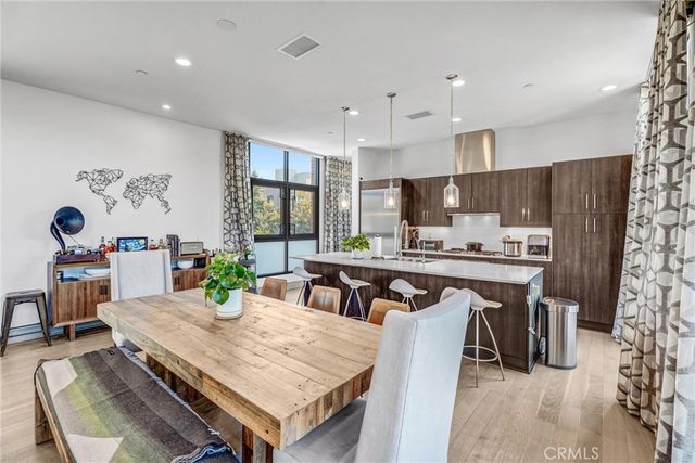 a kitchen with stainless steel appliances a dining table chairs refrigerator and microwave