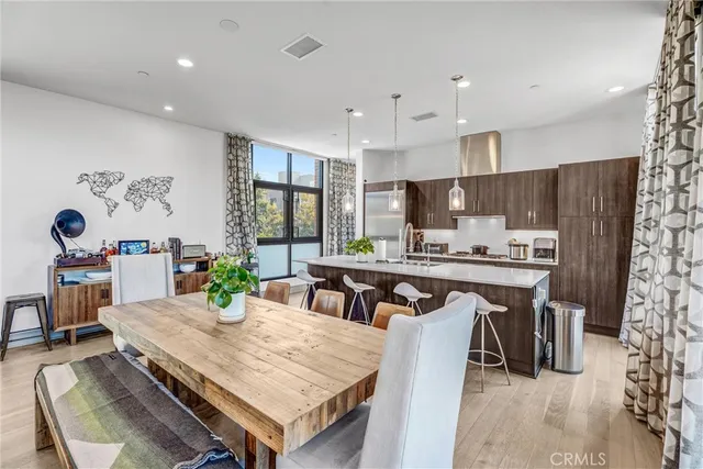 a kitchen with stainless steel appliances a dining table chairs refrigerator and microwave
