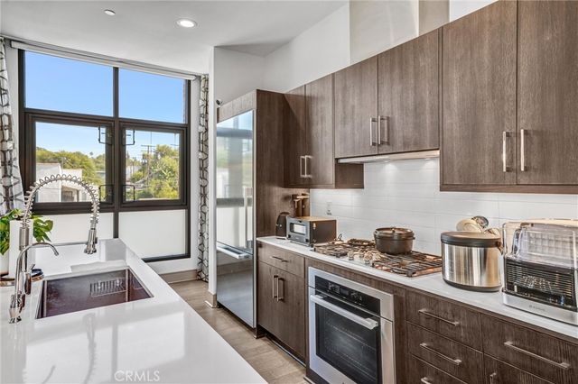 a room with stainless steel appliances kitchen island granite countertop a table chairs and a refrigerator
