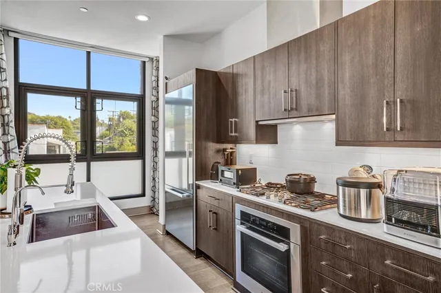 a room with stainless steel appliances kitchen island granite countertop a table chairs and a refrigerator