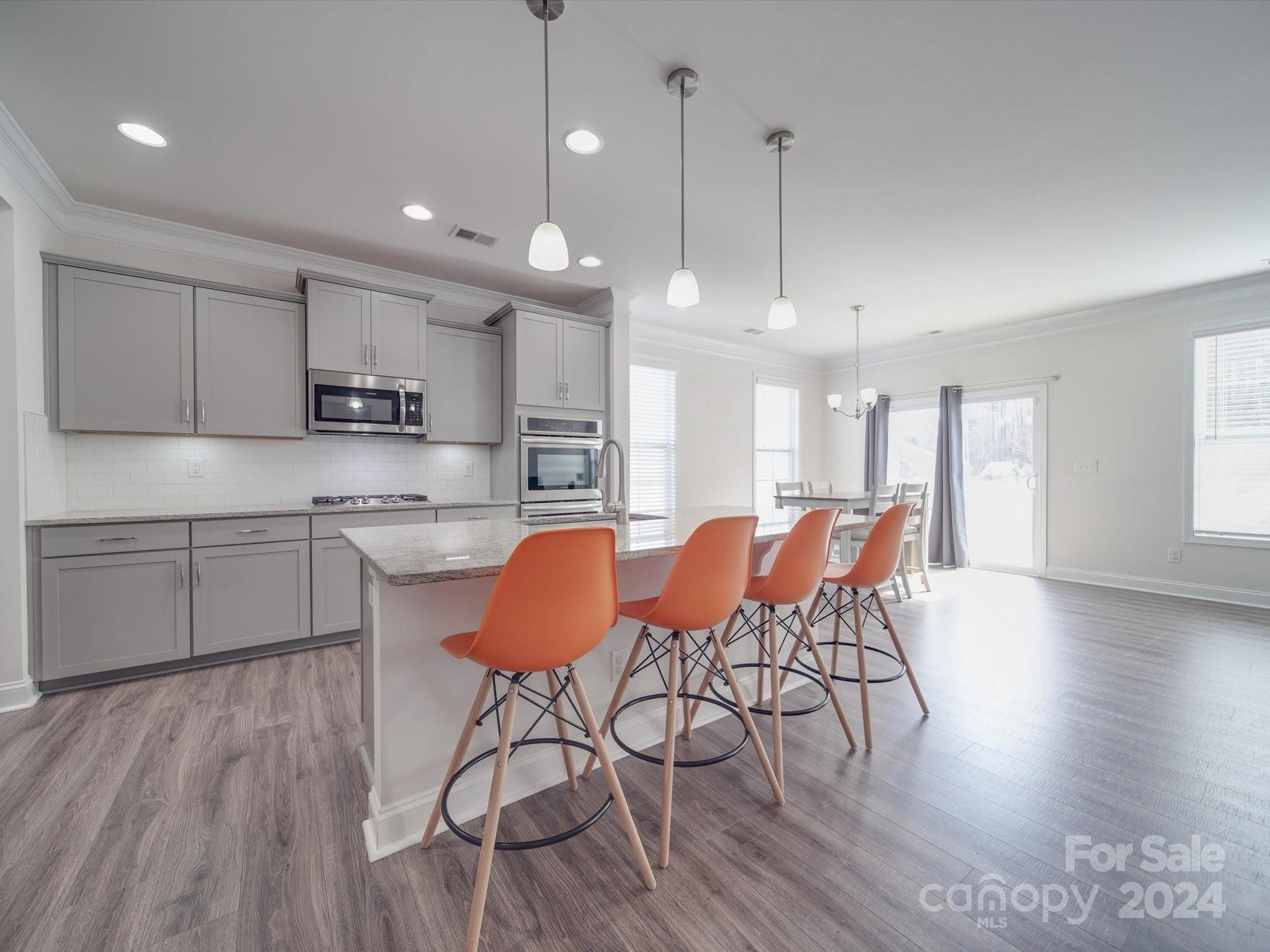 5901 Redwood Pine Road Concord, NC 28027 - Photo 11 of 39 a open kitchen with stainless steel appliances granite countertop a stove a refrigerator a kitchen island a dining table and chairs with wooden floor