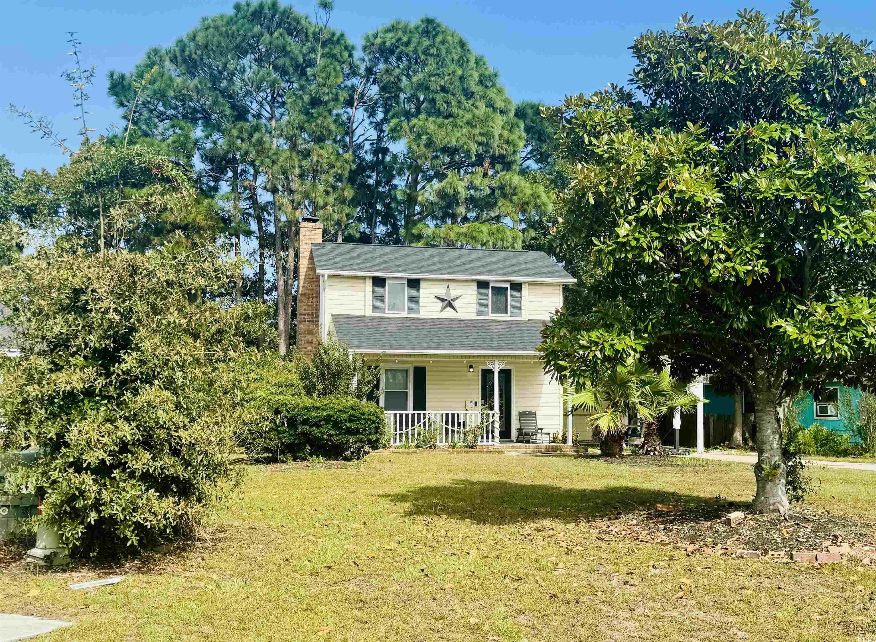 Traditional-style home featuring a chimney, a porch, and a front lawn