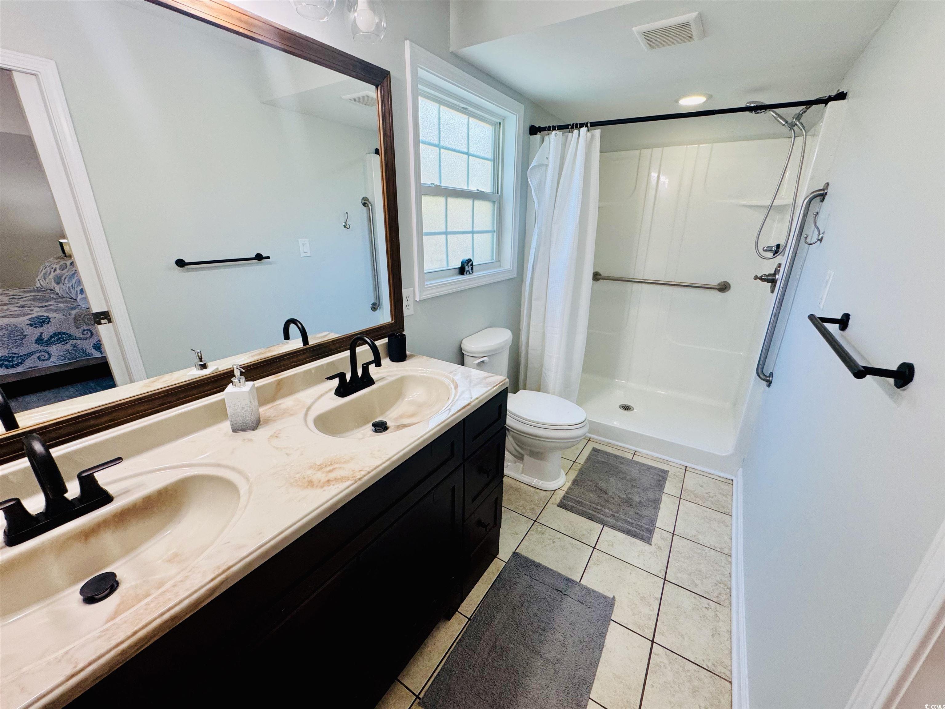 1960 Lake View Circle Surfside Beach, SC 29575 - Photo 23 of 40 Ensuite bathroom with double vanity, light tile patterned flooring, and a stall shower