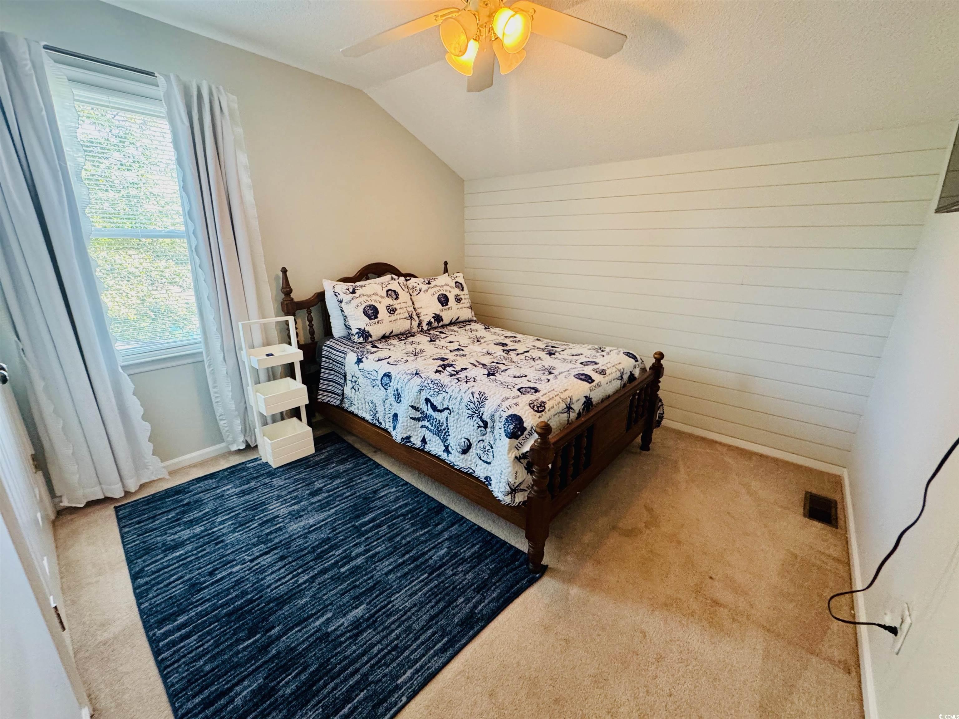 1960 Lake View Circle Surfside Beach, SC 29575 - Photo 27 of 40 Carpeted bedroom featuring lofted ceiling, wooden walls, a ceiling fan, and a textured ceiling