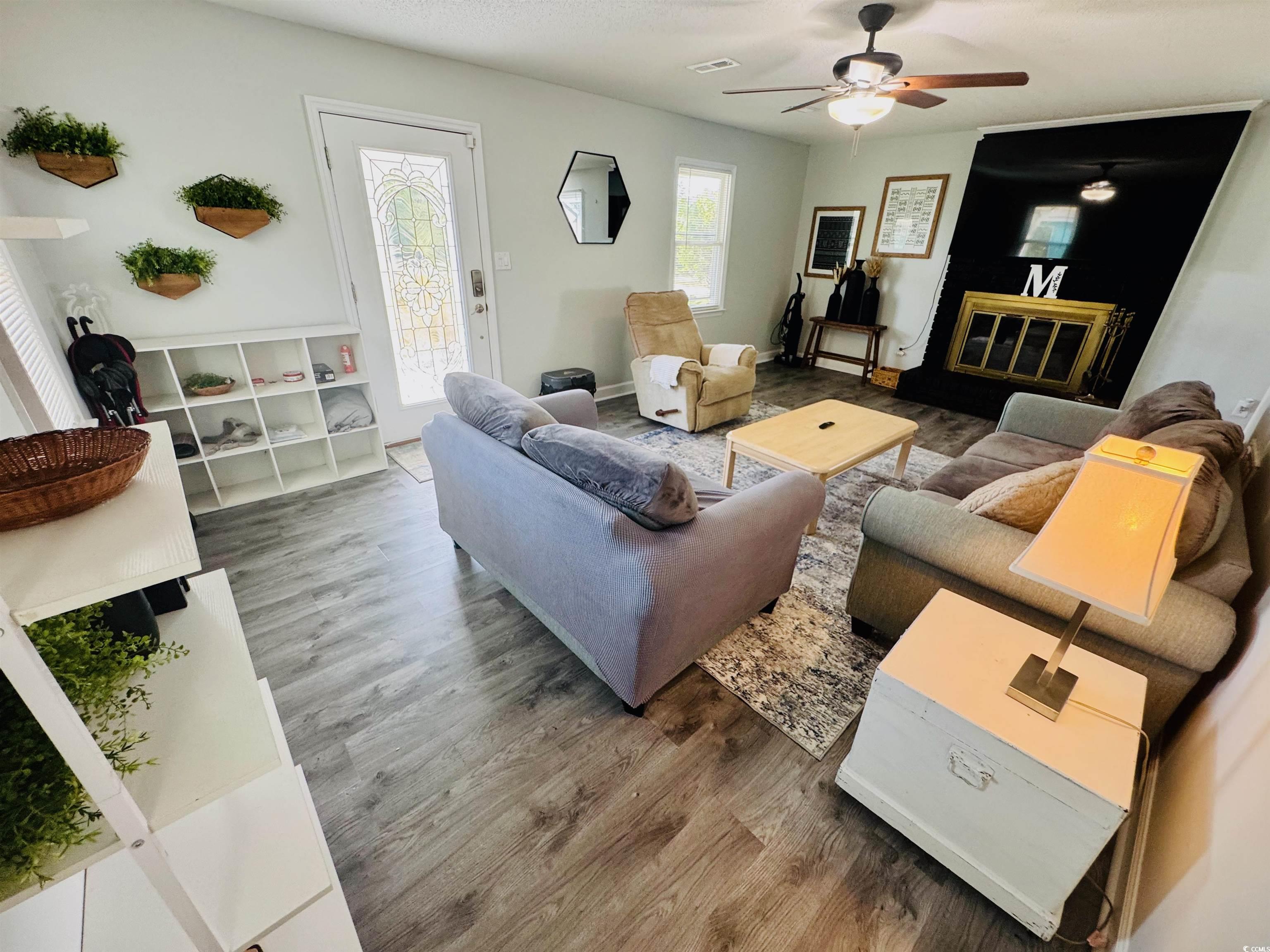 1960 Lake View Circle Surfside Beach, SC 29575 - Photo 7 of 40 Living area with wood finished floors, a ceiling fan, and a glass covered fireplace