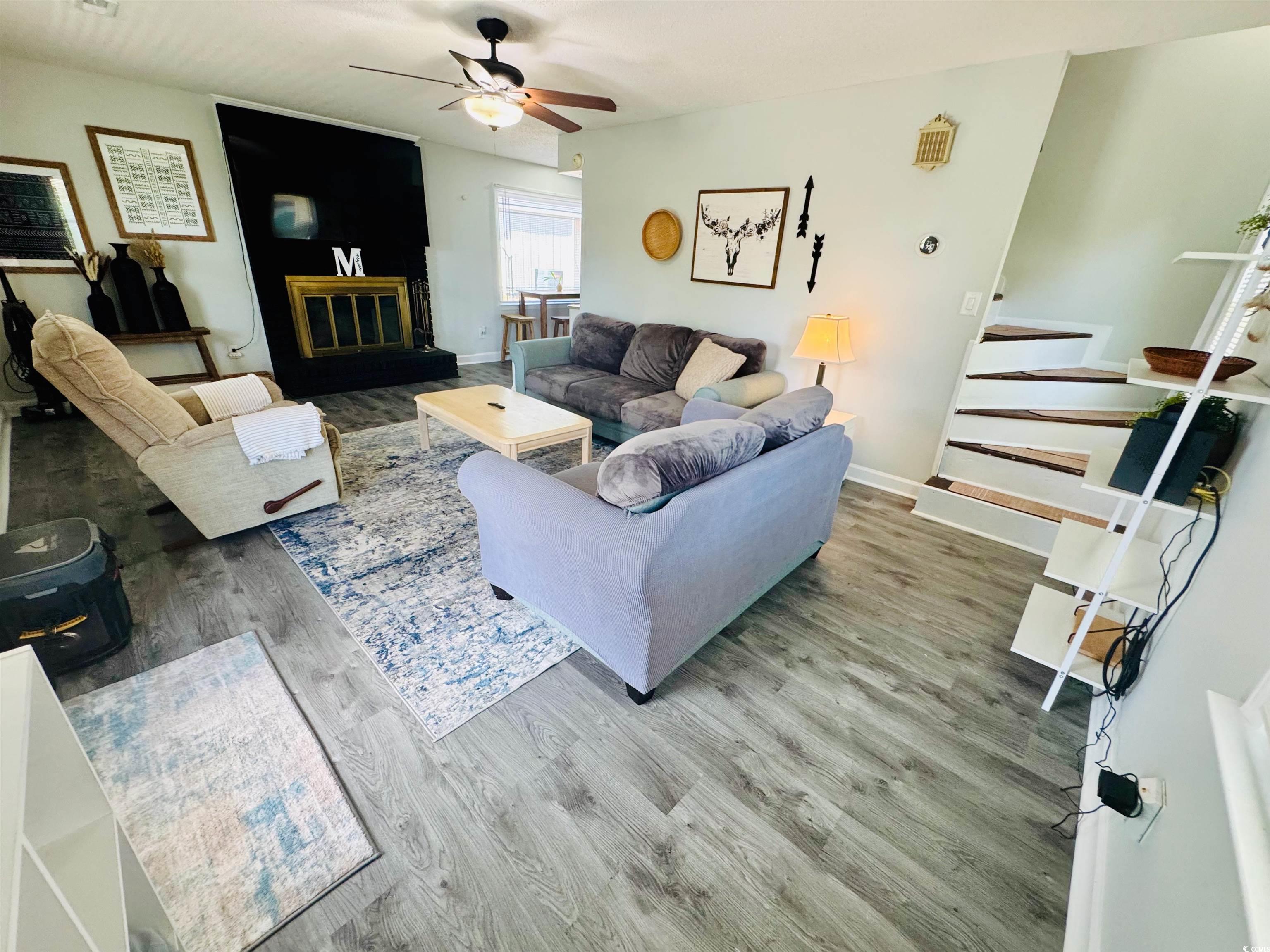 1960 Lake View Circle Surfside Beach, SC 29575 - Photo 9 of 40 Living room with wood finished floors, stairway, a ceiling fan, and a glass covered fireplace
