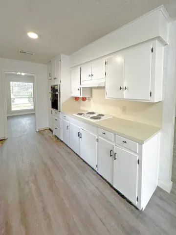 a large white kitchen with cabinets and wooden floor