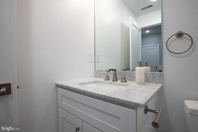 a bathroom with a granite countertop sink a toilet and a mirror