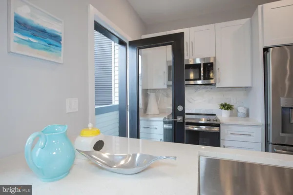 a kitchen with stainless steel appliances kitchen island granite countertop a refrigerator a stove a sink a microwave a dining table and chairs with wooden floor