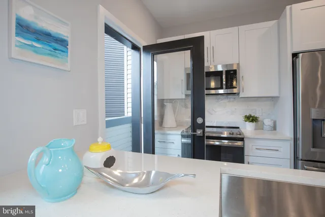 a kitchen with stainless steel appliances kitchen island granite countertop a refrigerator a stove a sink a microwave a dining table and chairs with wooden floor