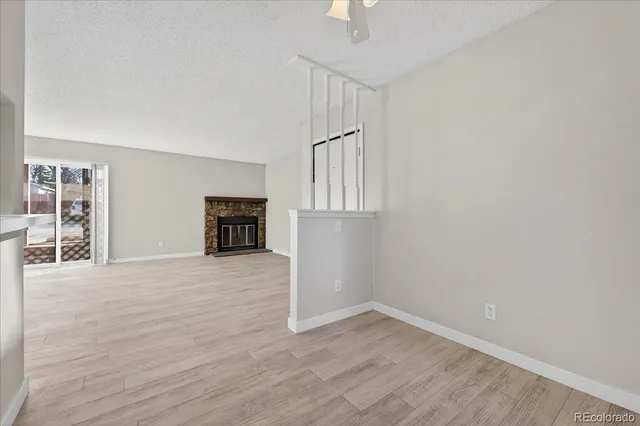 a view of an empty room with wooden floor kitchen and a window