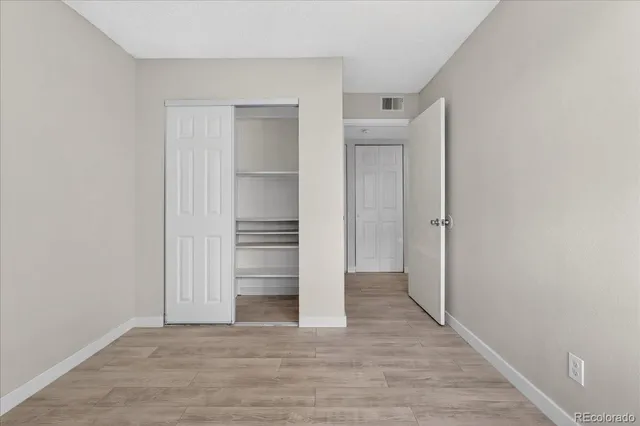 a view of an empty room with wooden floor and closet